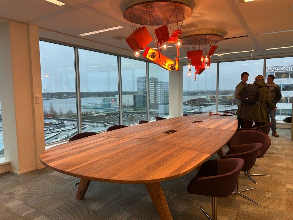 Het afgewerkte The Boardroom van Floor Almere met maatwerk houten tafel en design hanglamp