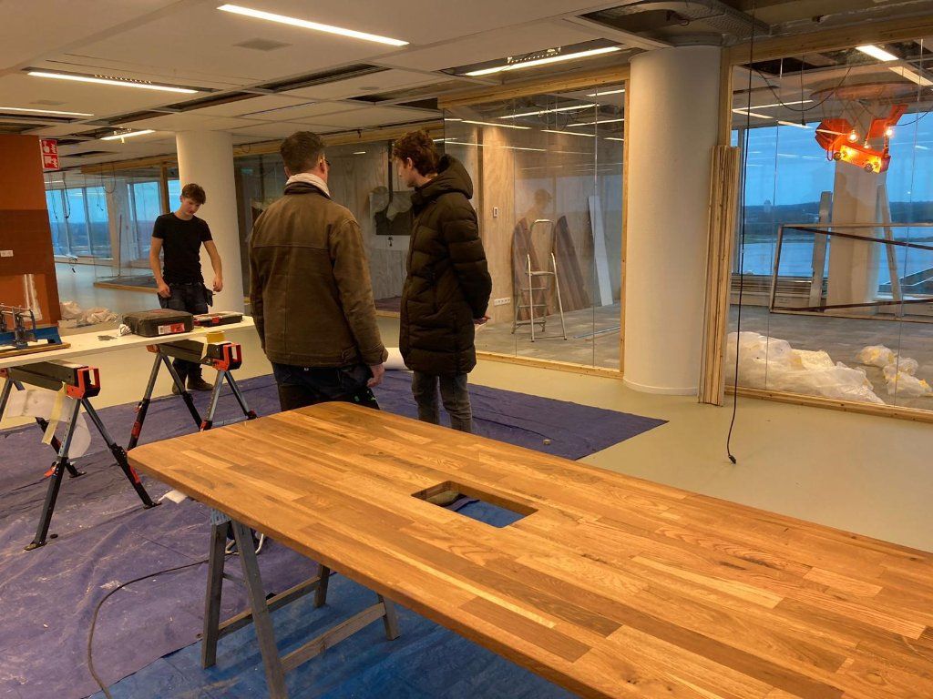 Team van makers werkt aan een houten tafel tijdens de bouwfase van Floor Almere